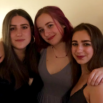 Three young women pose together.